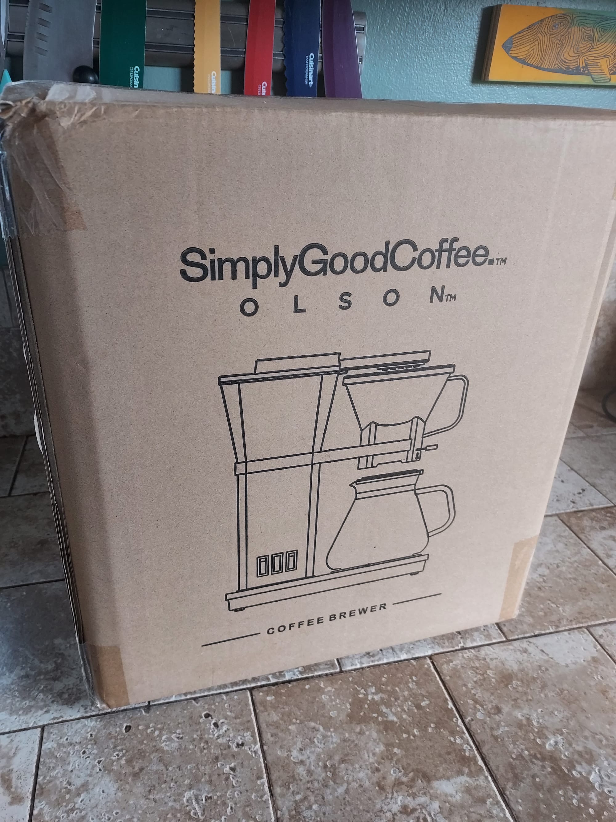 A brown cardboard box with a line-drawing illustration of a coffee brewer on the side.