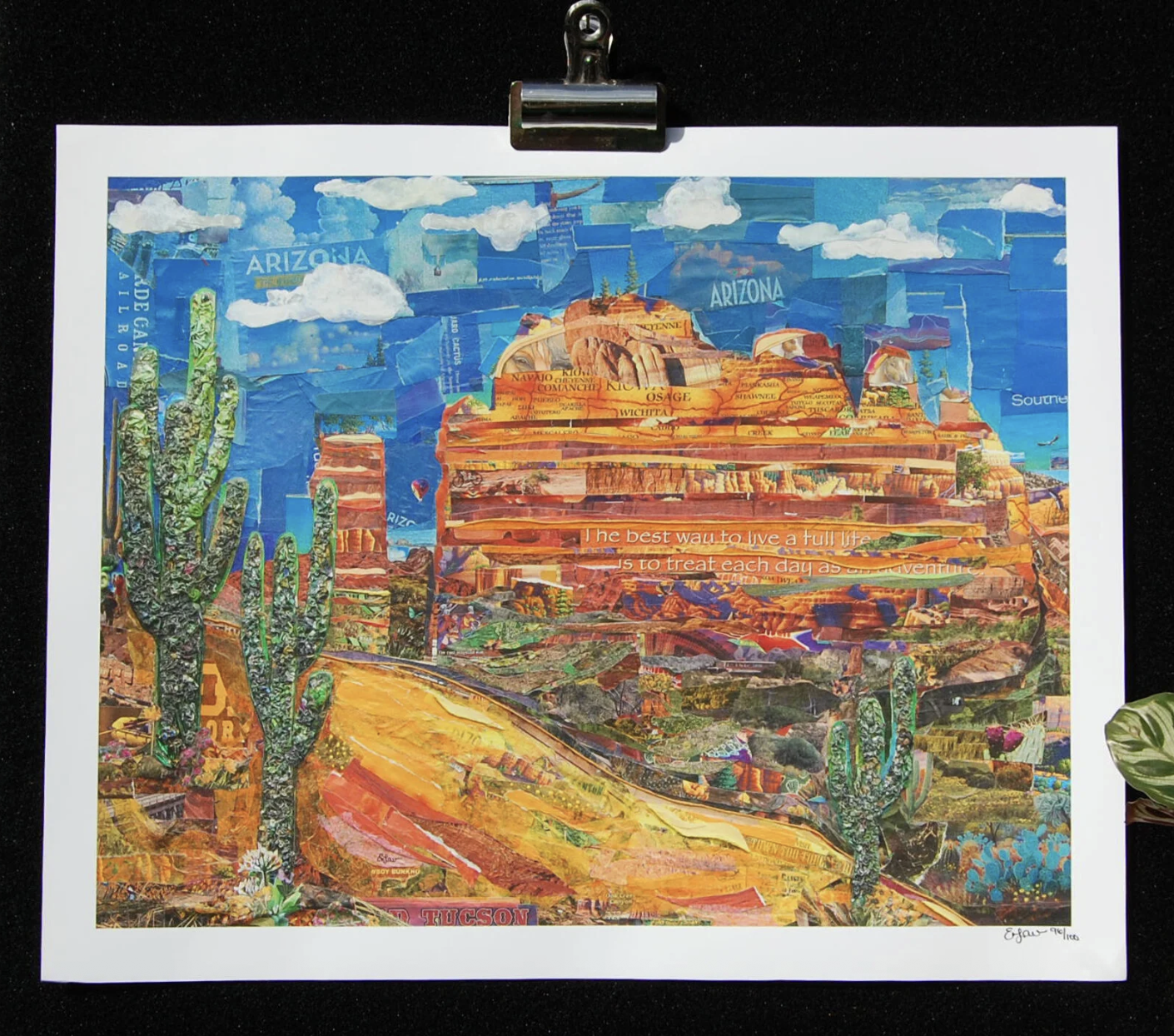 A close up of a cut paper collage laid out as the red rock Sedona, AZ landscape with tall green saguaro cactus reaching up into the blue sky.